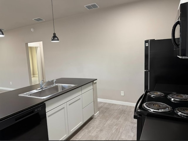 427 Pintail Loop, San Marcos, TX 78666 - kitchen with black appliances, white cabinetry, dark countertops, light wood-style floors, and pendant lighting