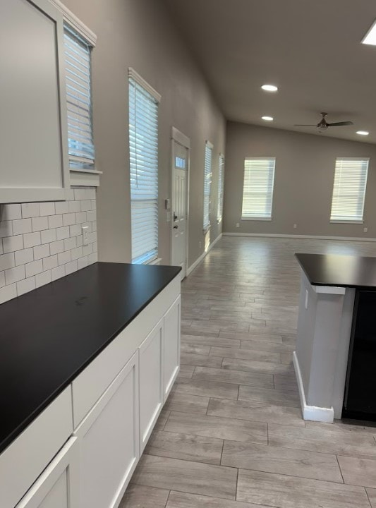 427 Pintail Loop, San Marcos, TX 78666 - kitchen with dark countertops, open floor plan, a ceiling fan, tasteful backsplash, and white cabinetry