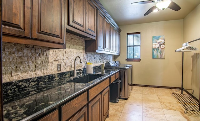 kitchen with ceiling fan, sink, dark stone counters, washer and clothes dryer, and light tile patterned flooring