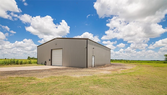 view of outbuilding featuring a lawn, a rural view, and a garage