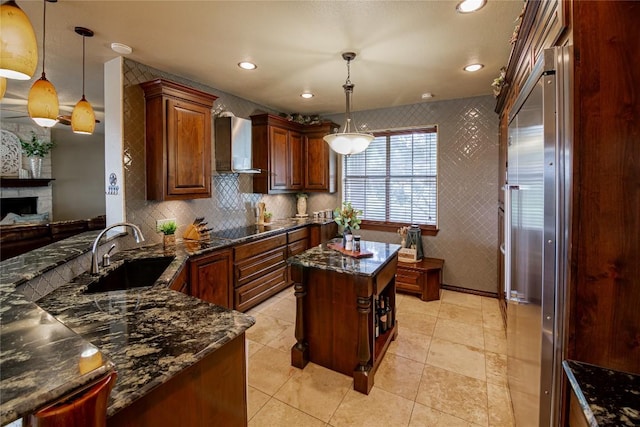 kitchen featuring sink, a kitchen island, hanging light fixtures, and wall chimney range hood