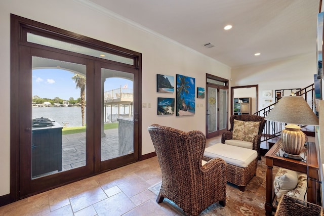 sitting room with crown molding, french doors, and a water view