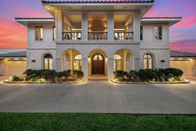 mediterranean / spanish home featuring a garage and a balcony