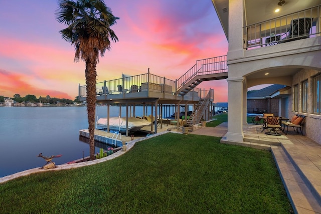 dock area with a patio, a water view, and a lawn