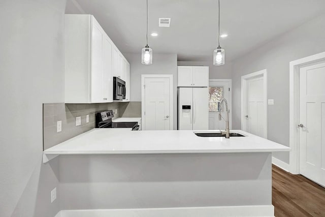 kitchen with kitchen peninsula, sink, appliances with stainless steel finishes, decorative light fixtures, and white cabinetry