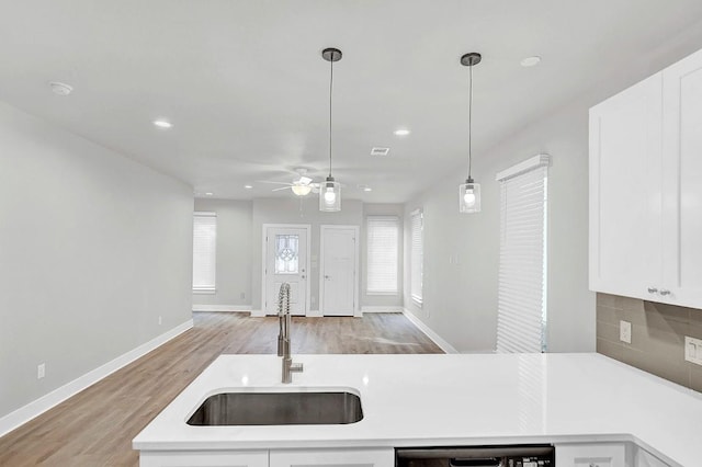 kitchen with dishwasher, sink, pendant lighting, and light hardwood / wood-style flooring