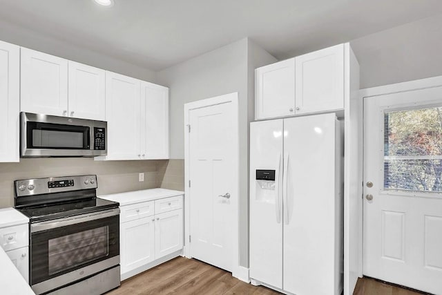 kitchen featuring white cabinets, appliances with stainless steel finishes, decorative backsplash, and wood-type flooring