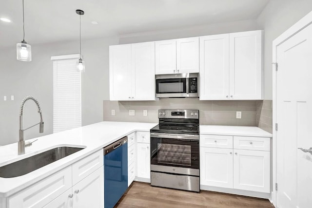 kitchen featuring sink, stainless steel appliances, backsplash, pendant lighting, and white cabinets