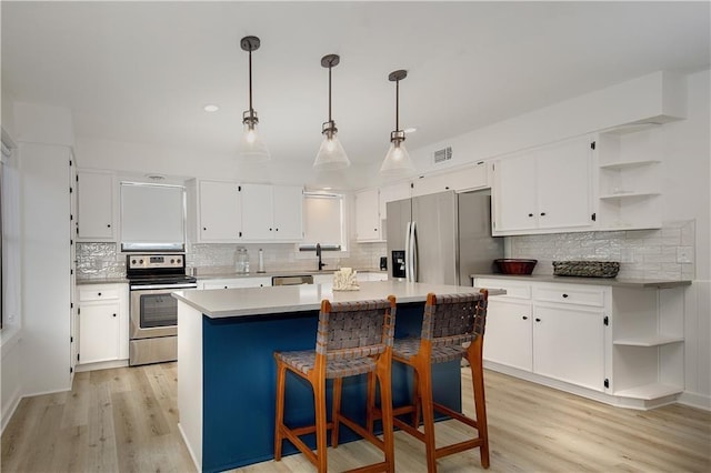 kitchen featuring pendant lighting, stainless steel appliances, and white cabinetry