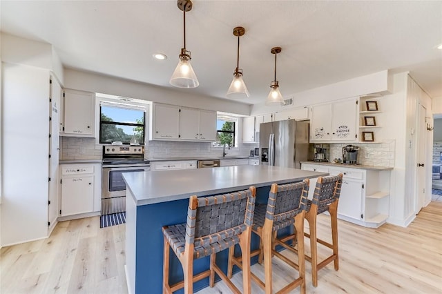 kitchen with sink, white cabinets, hanging light fixtures, and appliances with stainless steel finishes