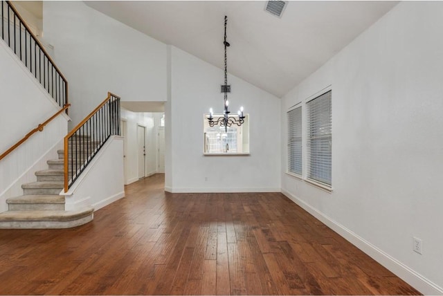 unfurnished dining area featuring a notable chandelier, dark wood-type flooring, and high vaulted ceiling