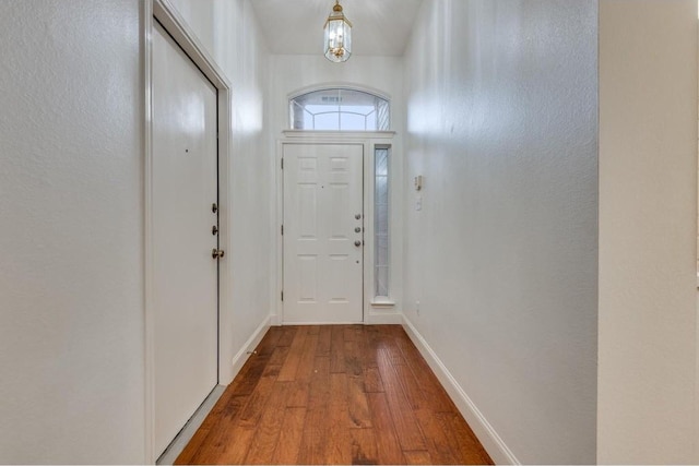 doorway to outside with wood-type flooring and an inviting chandelier