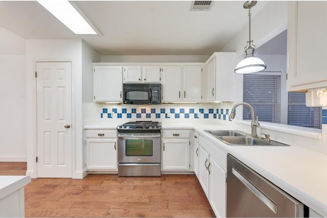 kitchen with decorative backsplash, stainless steel appliances, sink, decorative light fixtures, and white cabinets