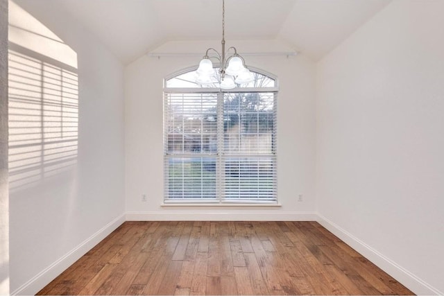 unfurnished dining area featuring wood-type flooring, vaulted ceiling, and a notable chandelier