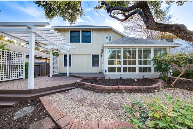 back of property featuring a pergola, a wooden deck, and a sunroom