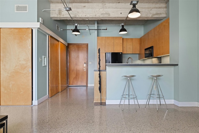 710 Colorado St Unit 5F, Austin, TX 78701 - kitchen with refrigerator, black microwave, a towering ceiling, speckled floor, and baseboards