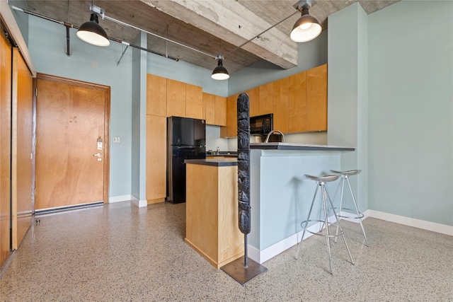 kitchen featuring kitchen peninsula, pendant lighting, and black appliances