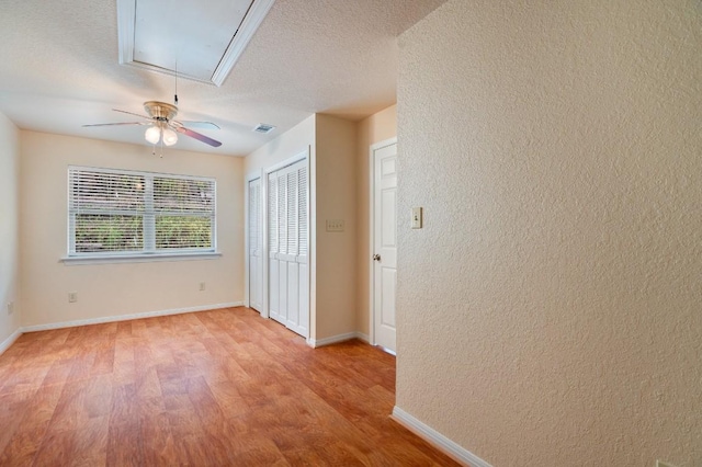 unfurnished bedroom with ceiling fan, a textured ceiling, and light wood-type flooring