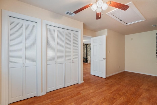 unfurnished bedroom with multiple closets, ceiling fan, and light hardwood / wood-style floors