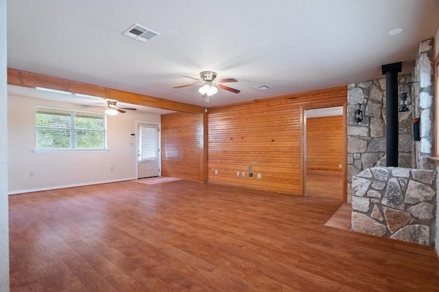 unfurnished living room with wooden walls, ceiling fan, and hardwood / wood-style flooring