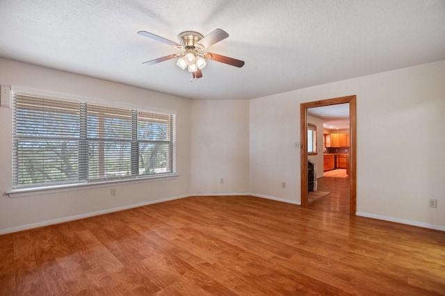 spare room featuring a textured ceiling, light wood-type flooring, and ceiling fan