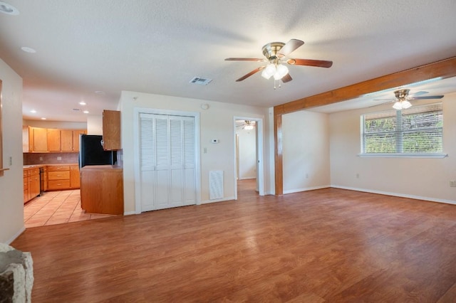 unfurnished living room with a textured ceiling and light hardwood / wood-style flooring