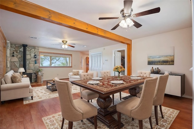 118 S S Cv, Spicewood, TX 78669 - dining room featuring ceiling fan, a wood stove, dark wood-type flooring, and beam ceiling
