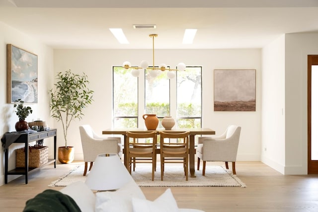 dining area with light hardwood / wood-style floors and an inviting chandelier