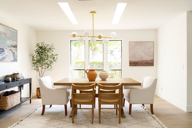 dining area with light hardwood / wood-style flooring and an inviting chandelier