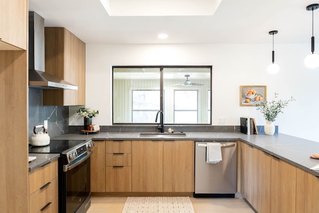 kitchen featuring appliances with stainless steel finishes, backsplash, sink, wall chimney range hood, and hanging light fixtures