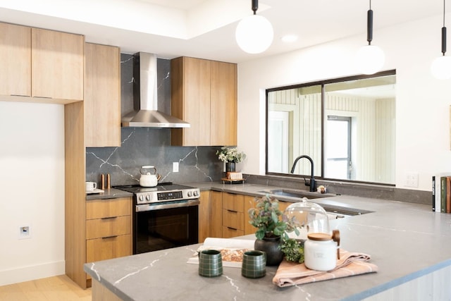 kitchen featuring pendant lighting, stainless steel range with electric stovetop, wall chimney range hood, and sink