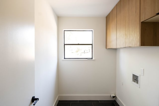 laundry area featuring cabinets and dark tile patterned flooring