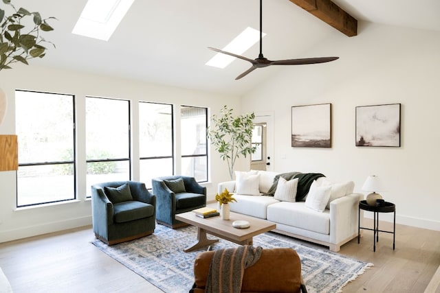 living room with ceiling fan, plenty of natural light, light hardwood / wood-style flooring, and vaulted ceiling with skylight