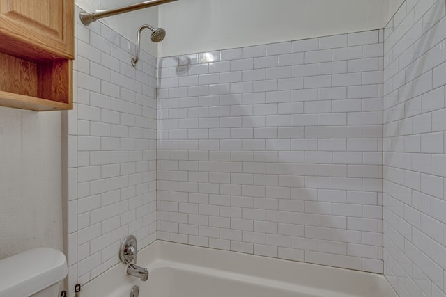 bathroom featuring toilet and tiled shower / bath