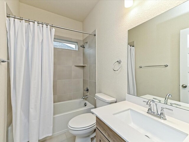 bathroom featuring a textured wall, toilet, shower / bath combo with shower curtain, vanity, and tile patterned flooring