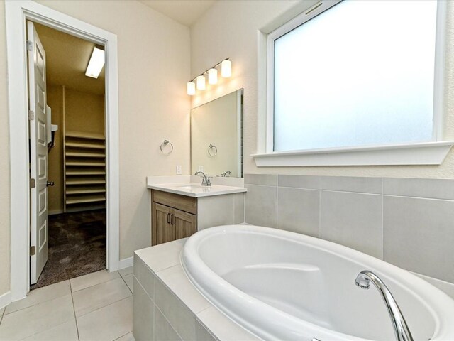 bathroom featuring tile patterned floors, a spacious closet, vanity, baseboards, and a bath