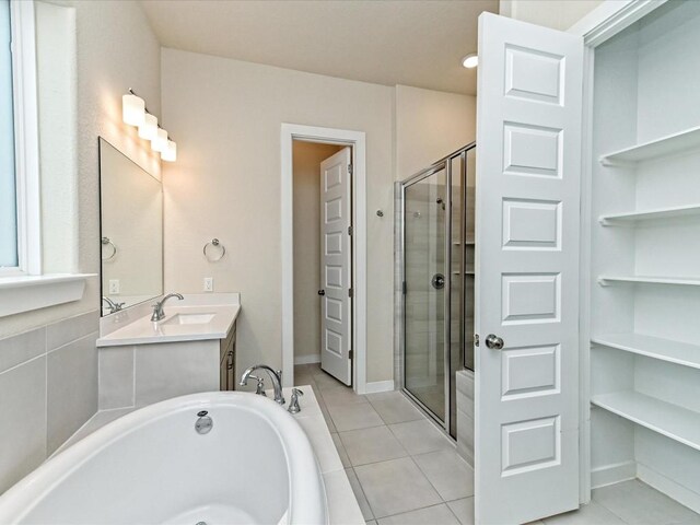 full bath featuring a stall shower, vanity, tile patterned flooring, baseboards, and a bath