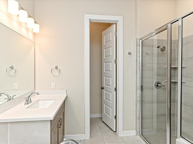 bathroom with a stall shower, tile patterned flooring, baseboards, and vanity