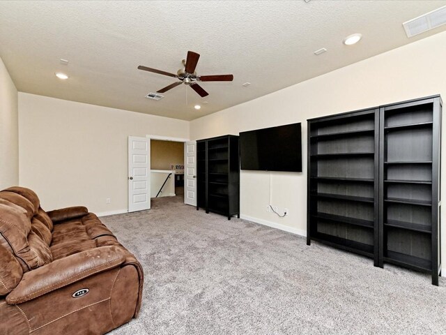 living room with carpet, a textured ceiling, visible vents, and baseboards