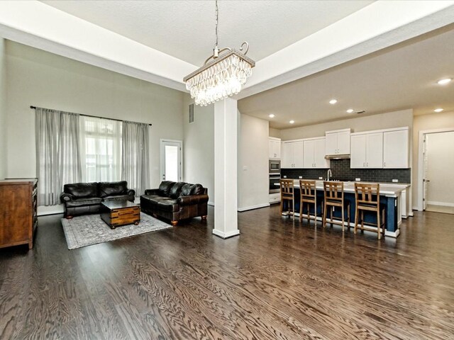 living room with a chandelier, recessed lighting, dark wood-style flooring, and baseboards