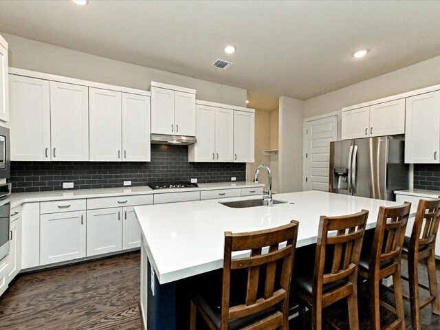 kitchen with a sink, visible vents, light countertops, decorative backsplash, and stainless steel fridge