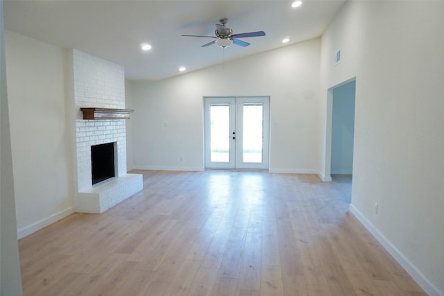 unfurnished living room with french doors, high vaulted ceiling, a brick fireplace, ceiling fan, and light hardwood / wood-style floors