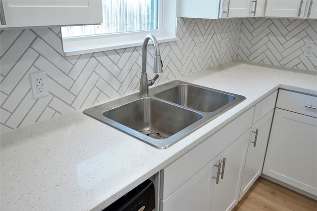 kitchen featuring tasteful backsplash, white cabinetry, sink, and light hardwood / wood-style flooring