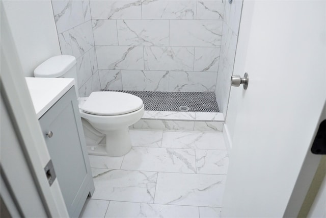 bathroom with vanity, toilet, and a tile shower