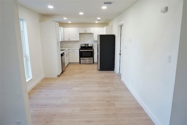 kitchen with tasteful backsplash, white cabinetry, light hardwood / wood-style floors, and appliances with stainless steel finishes