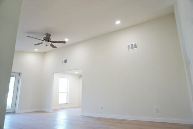 unfurnished room featuring light hardwood / wood-style flooring, ceiling fan, and a high ceiling