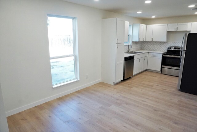 kitchen featuring white cabinetry, appliances with stainless steel finishes, backsplash, and light hardwood / wood-style flooring