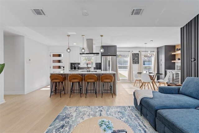 living room with light hardwood / wood-style floors, an inviting chandelier, and sink