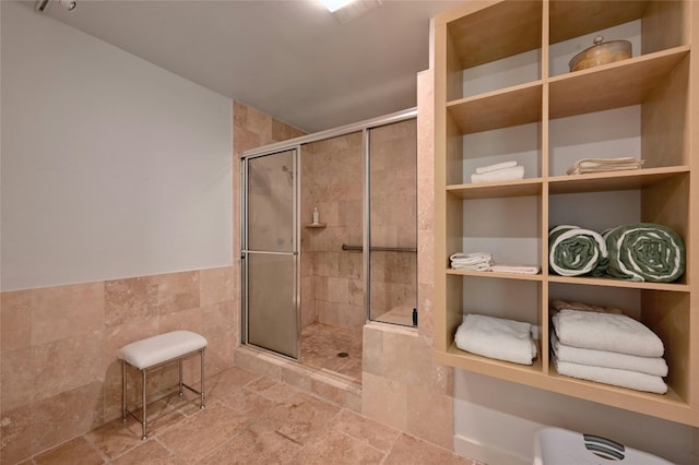 bathroom with a tile shower and tile walls