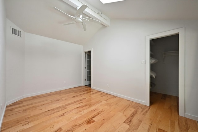 unfurnished bedroom with lofted ceiling with beams, light hardwood / wood-style flooring, ceiling fan, a spacious closet, and a closet